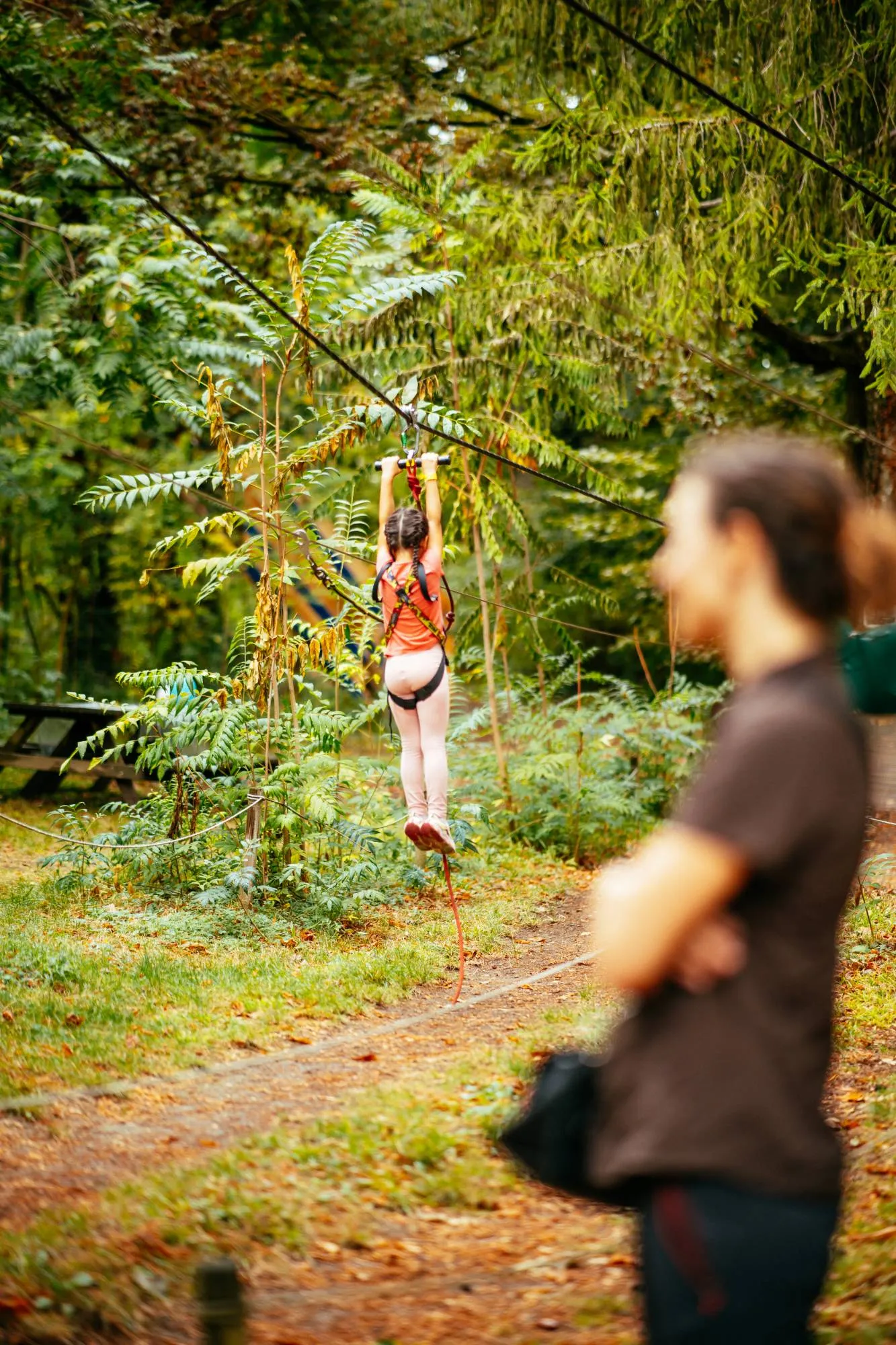 Petite fille suspendue à une tyrolienne dans la forêt d'automne