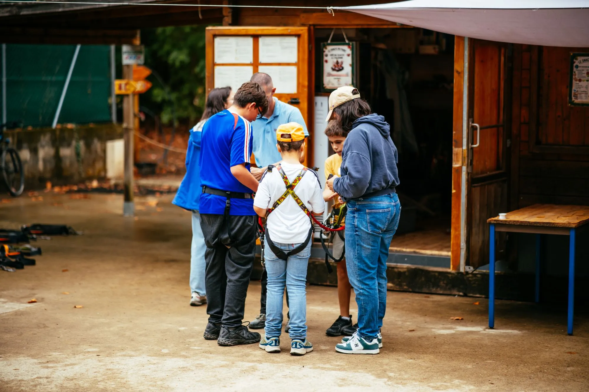 Un opérateur ajuste les baudriers des enfants avant le départ sur les parcours